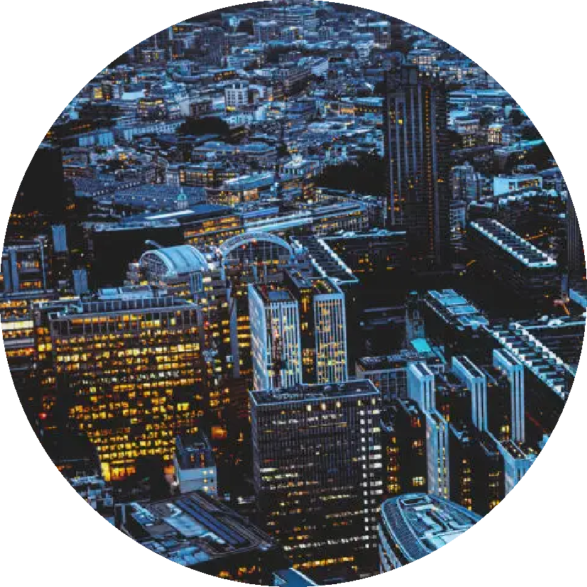 Aerial view of a city skyline at night with illuminated office buildings and streets.